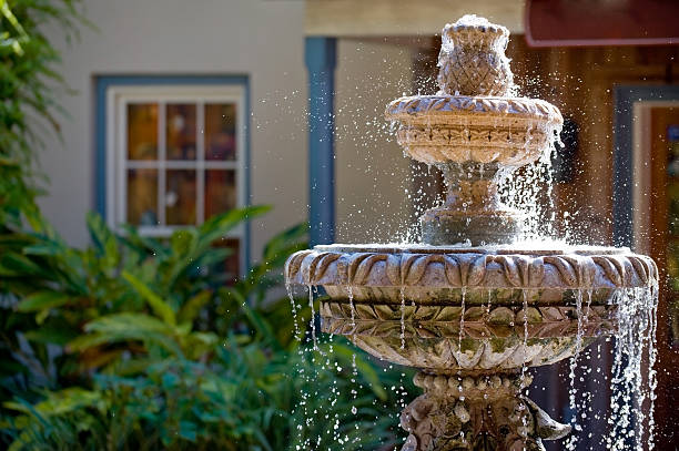 "A beautifully crafted small garden fountain with water cascading gracefully from a tiered design, surrounded by lush greenery and colorful flowers, creating a peaceful and relaxing outdoor ambiance."